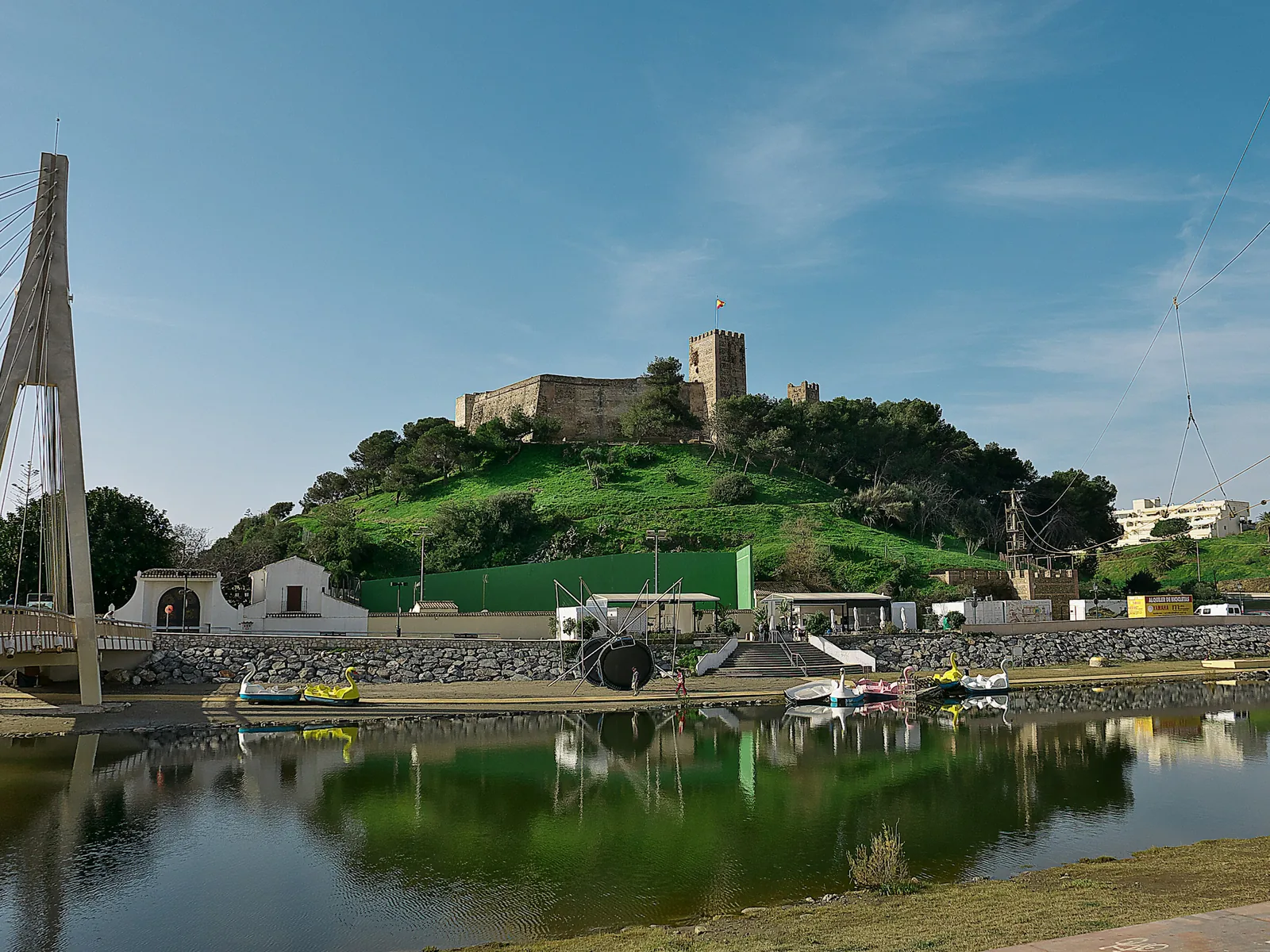 Castillo Sohail de Fuengirola en lo alto de su colina verde, con el río y el puente atirantado en primer plano